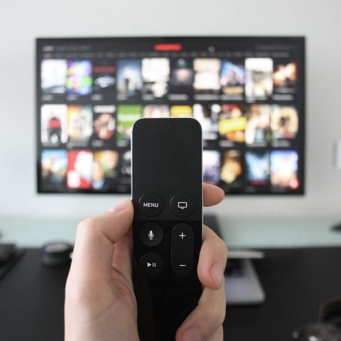 TV remote in foreground with flat-screen TV in background